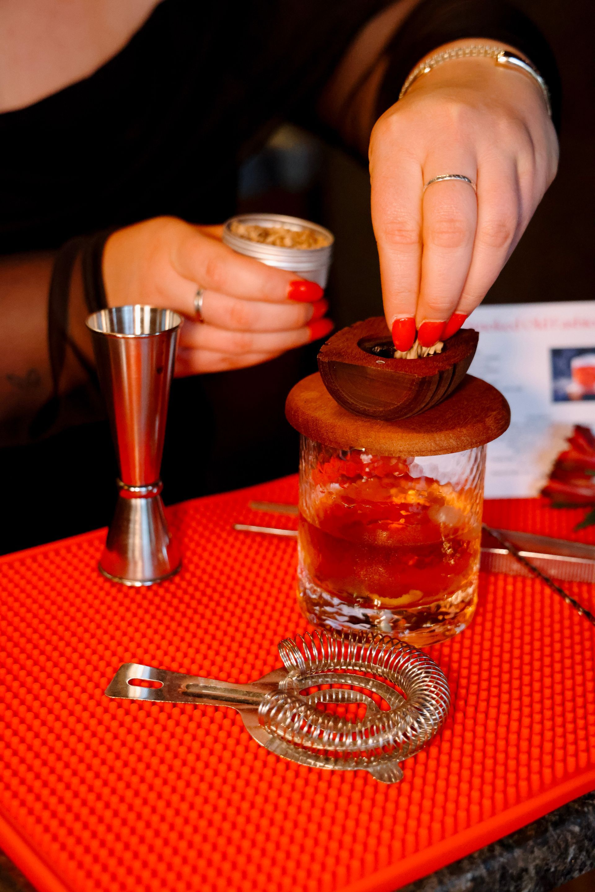 A woman is putting a cupcake on top of a glass of alcohol.
