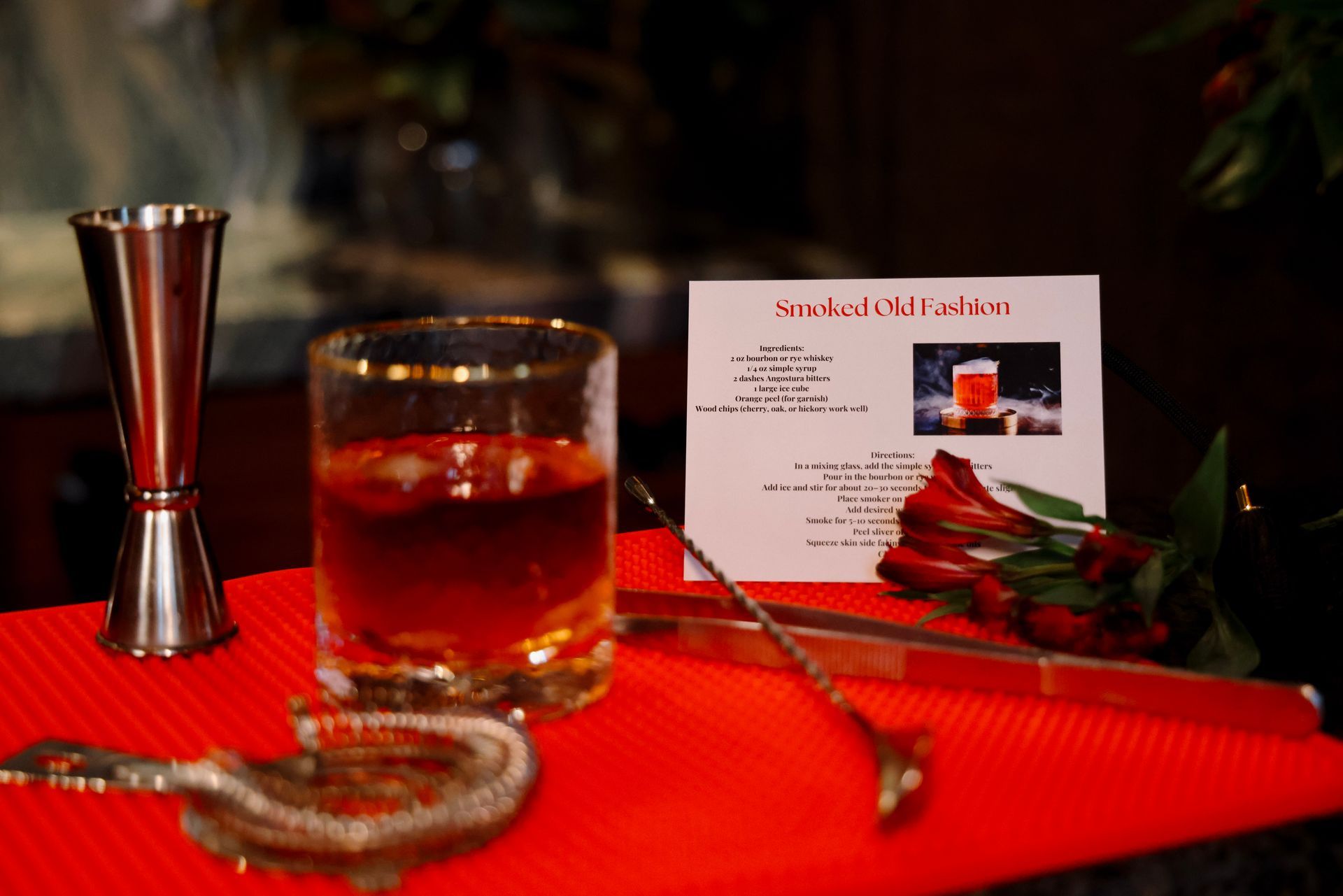 A glass of whiskey is sitting on a table next to a card.