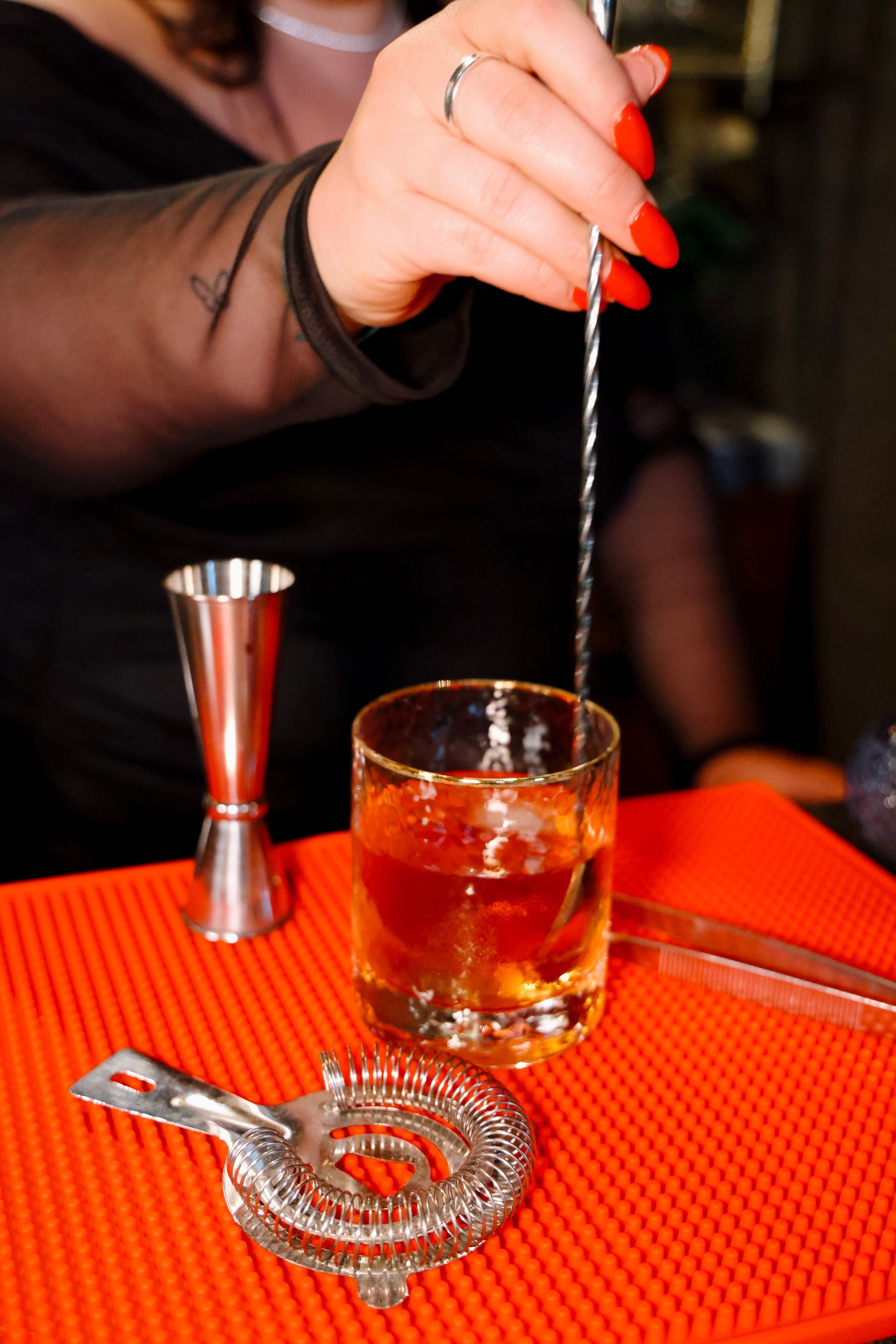 A woman is pouring a drink into a glass with a spoon.