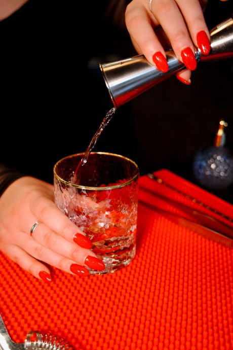 A martini glass is sitting on a table next to a green couch.