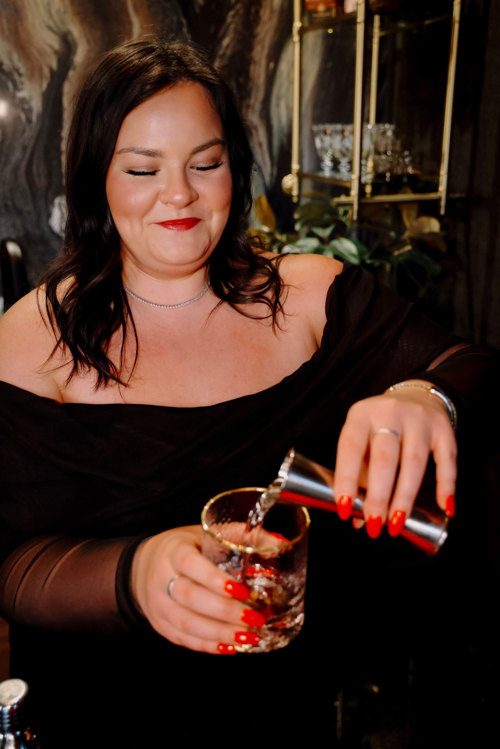 A woman is pouring a drink into a glass.