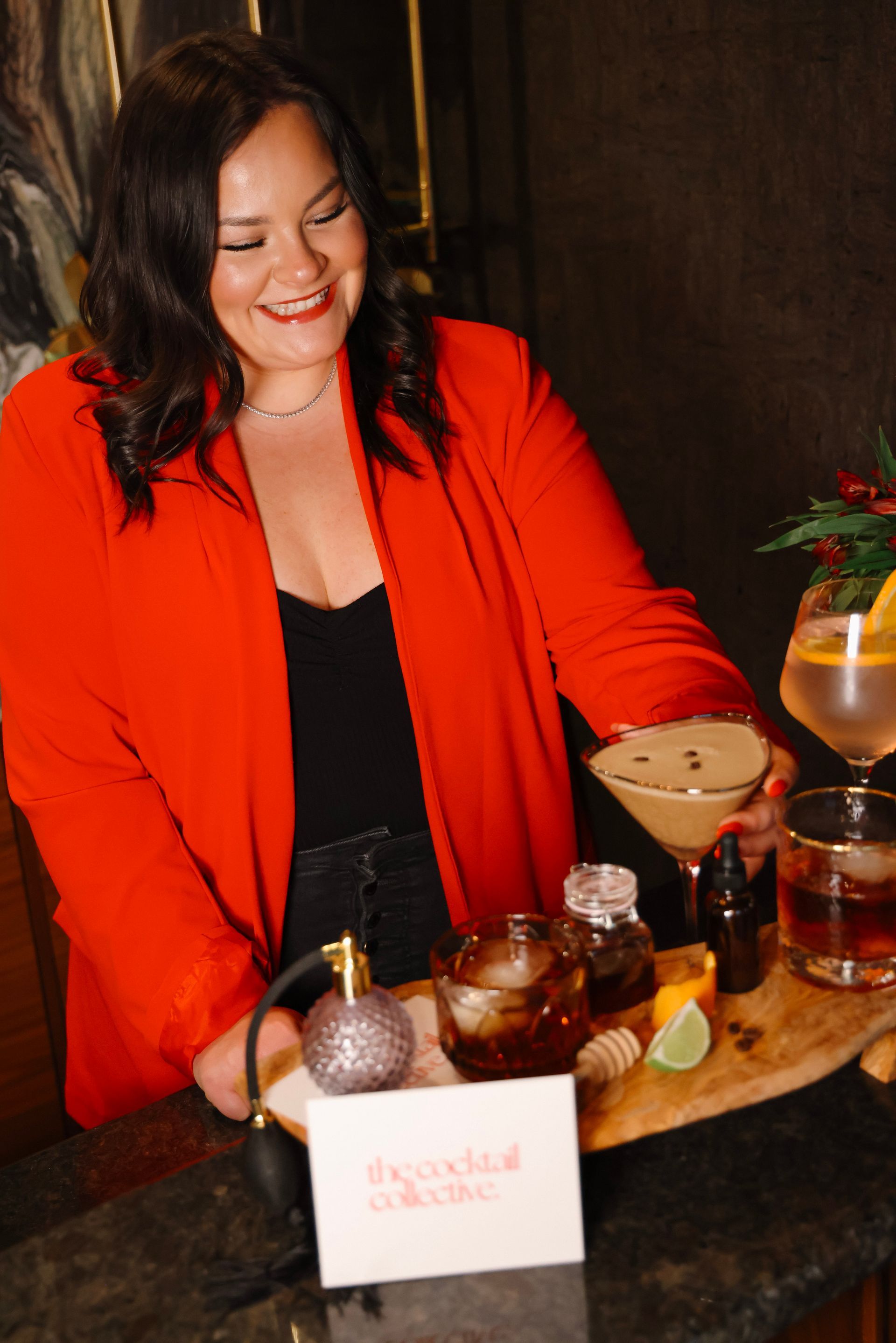 A woman in a red jacket is holding a martini in her hand.