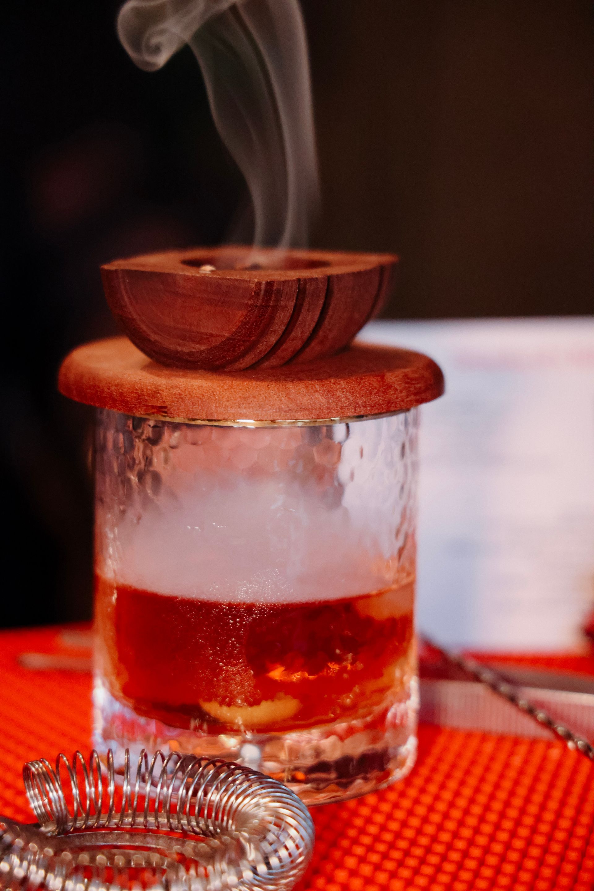 A glass of whiskey with smoke coming out of it on a table.