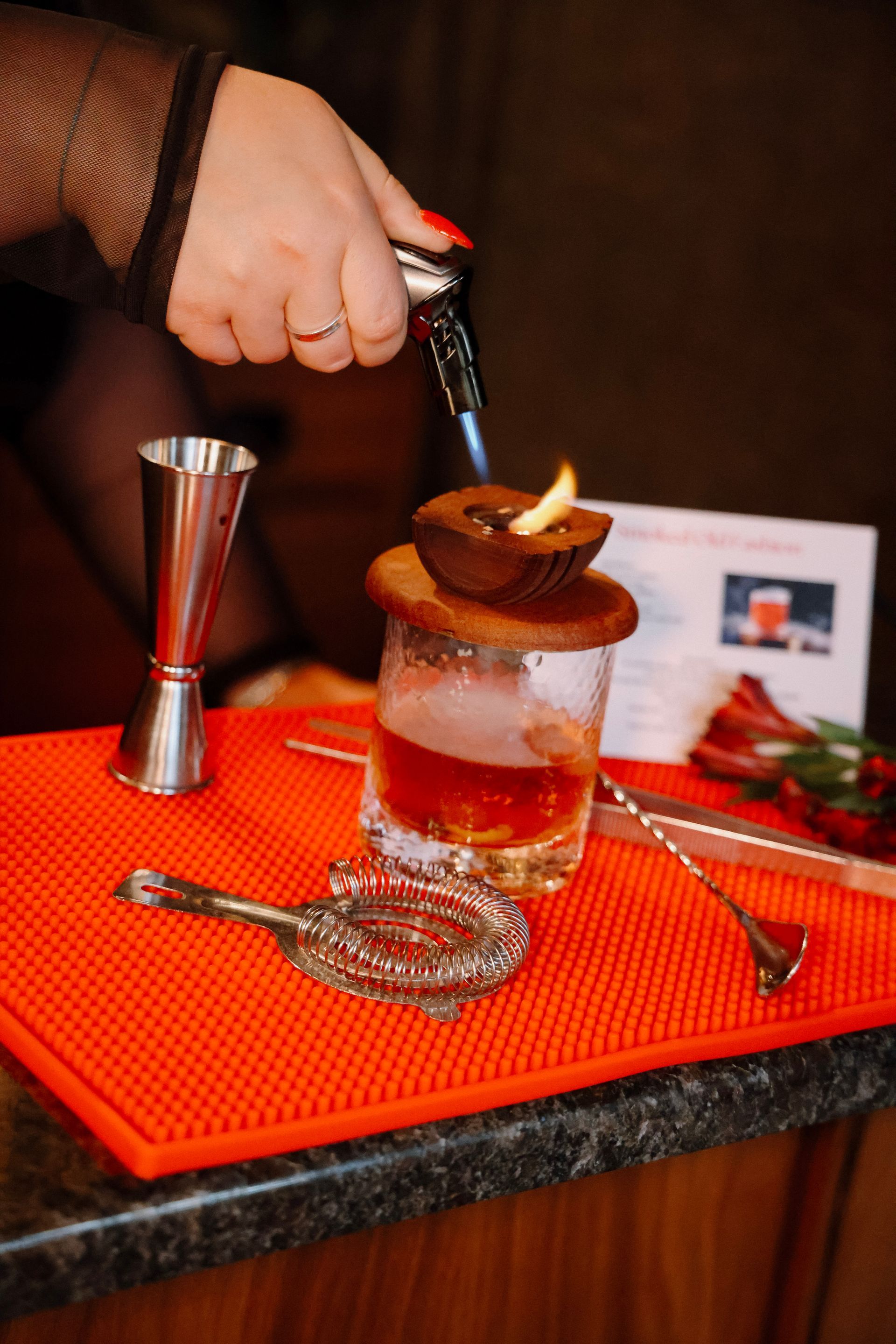 A person is pouring a drink into a glass with a candle on top of it.