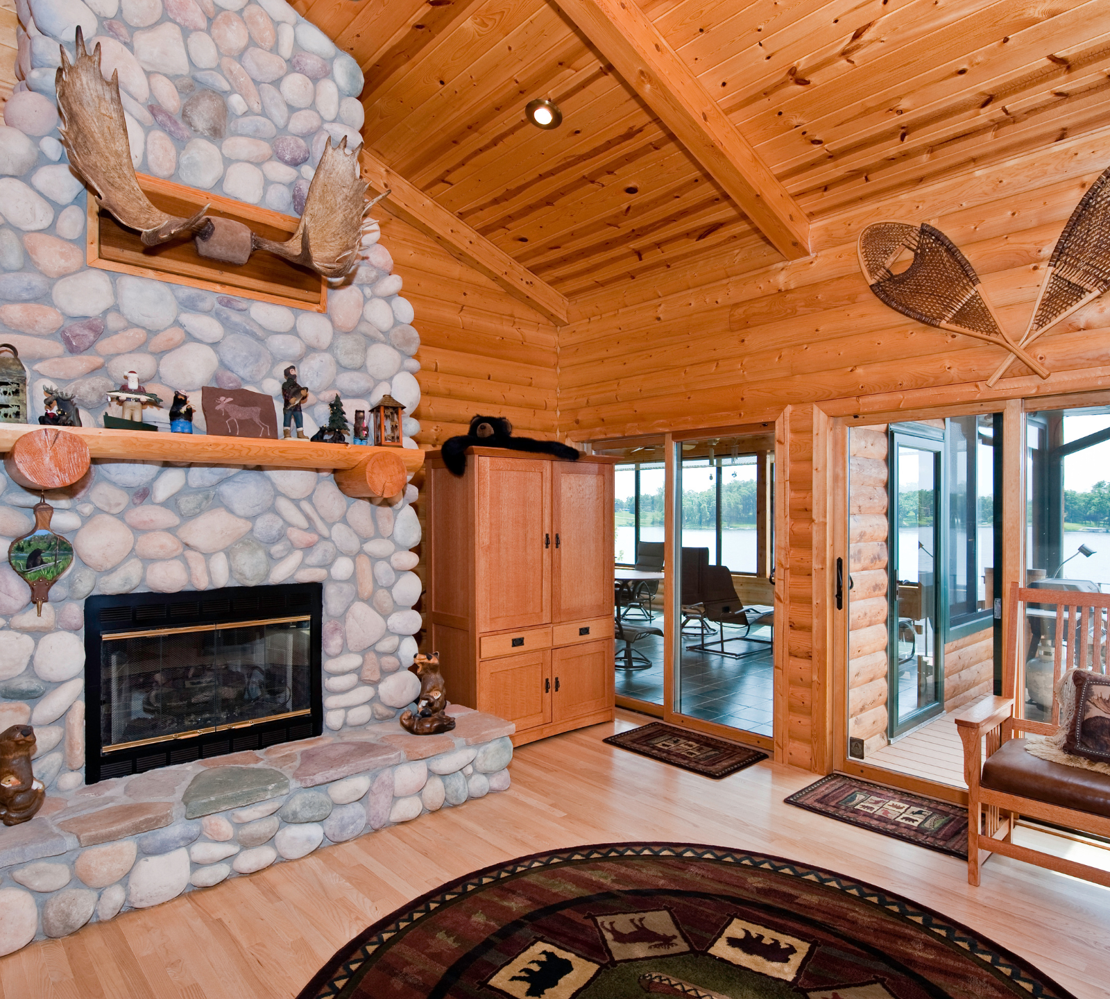 A living room with a stone fireplace and a rug