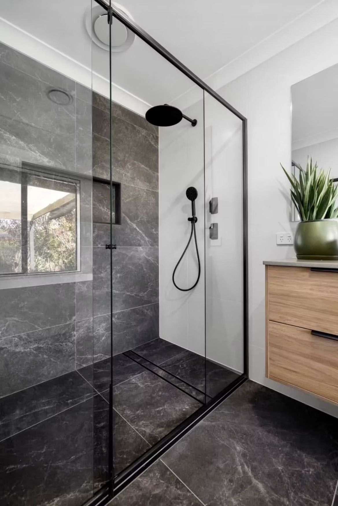 A bathroom with a walk in shower and a window.
