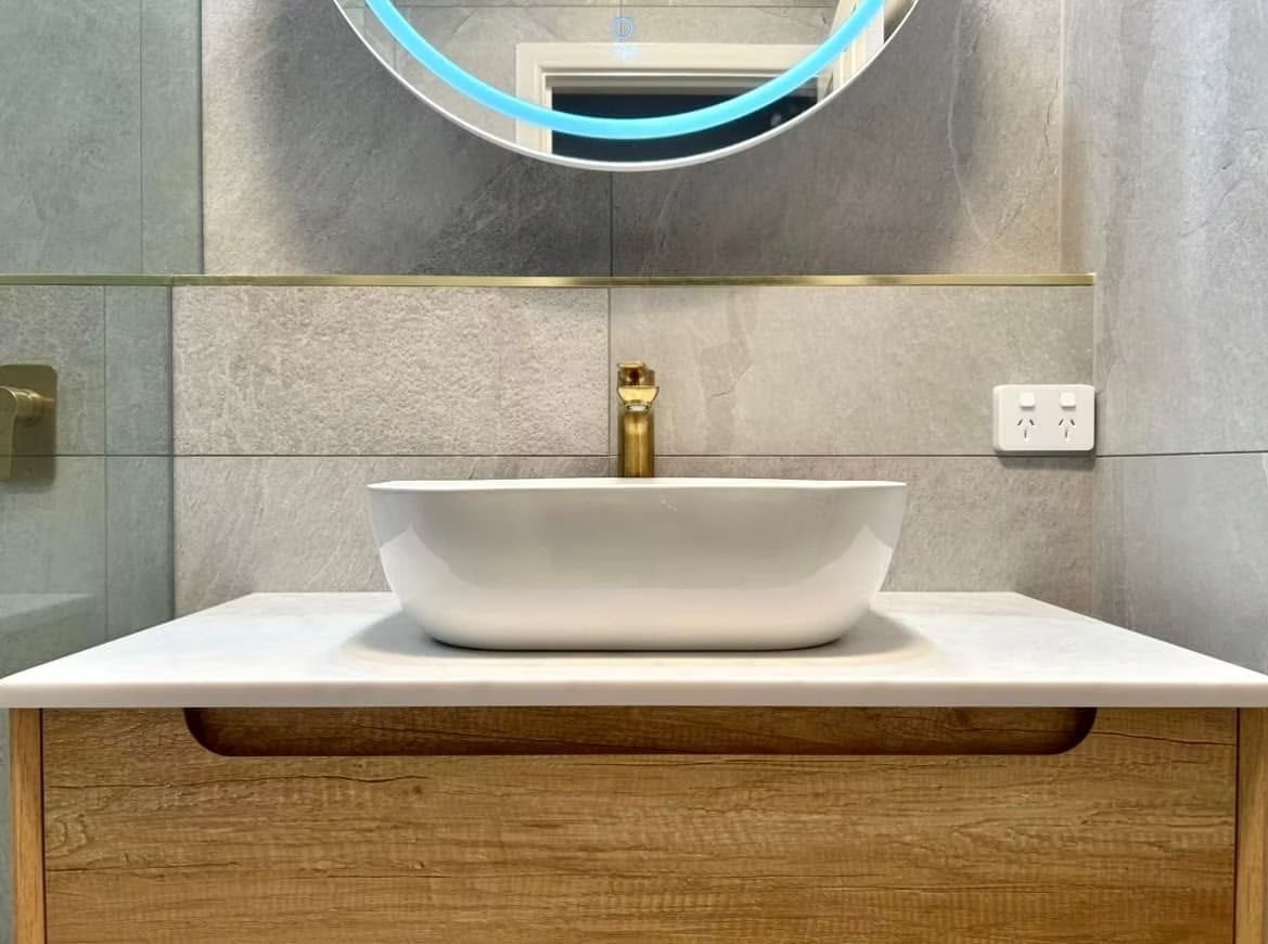 A bathroom with a sink and a round mirror.