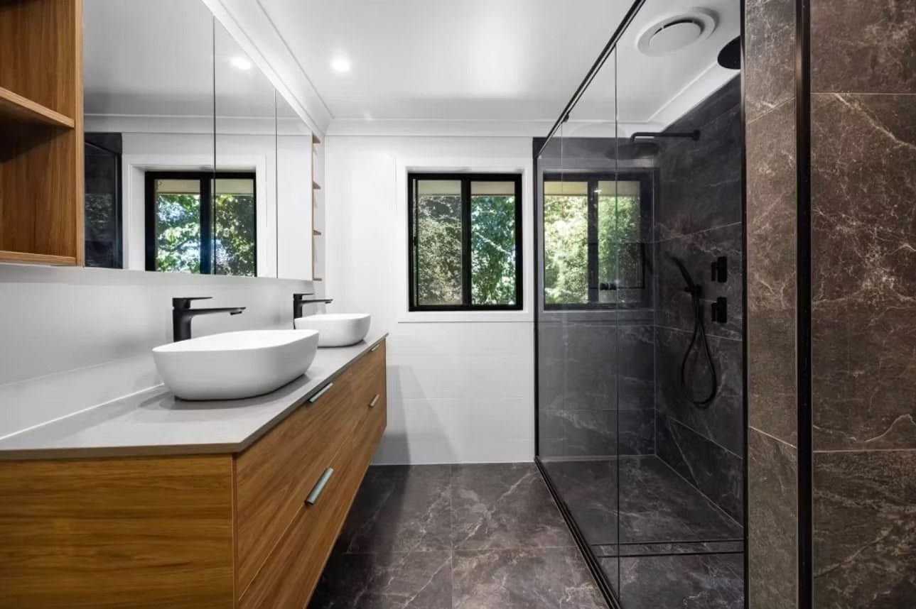 A bathroom with two sinks and a walk in shower.