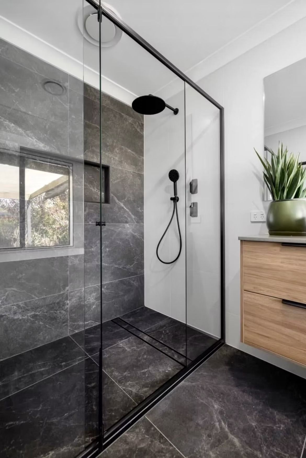 A bathroom with a walk in shower and a window.