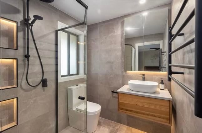 A bathroom with a toilet , sink , shower and mirror.