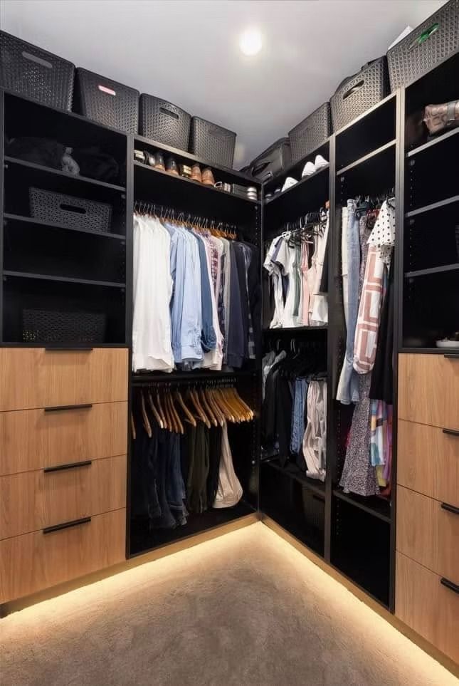 A walk in closet filled with lots of clothes and drawers.