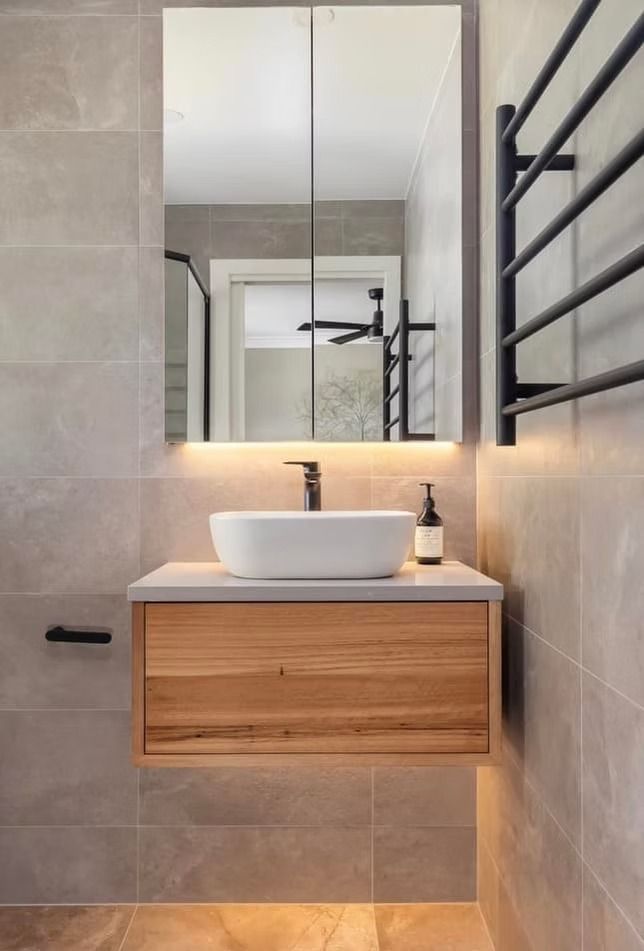 A bathroom with a sink , mirror and towel rack.