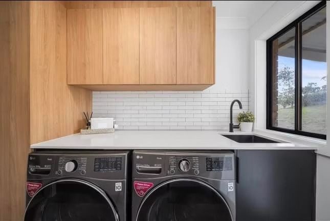 A laundry room with a washer and dryer and a sink.