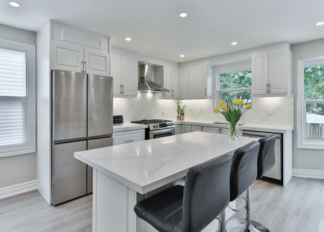 A kitchen with white cabinets , stainless steel appliances , and a large island.