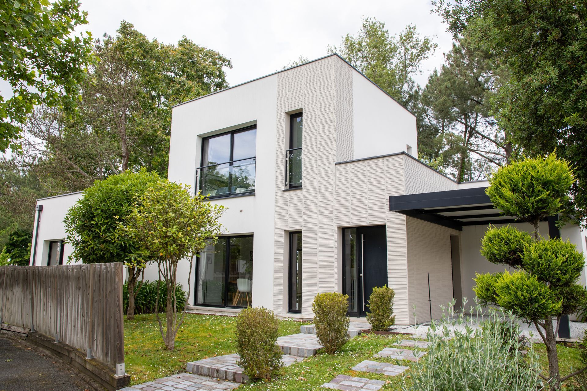 An aerial view of a white house with a blue roof and a driveway.