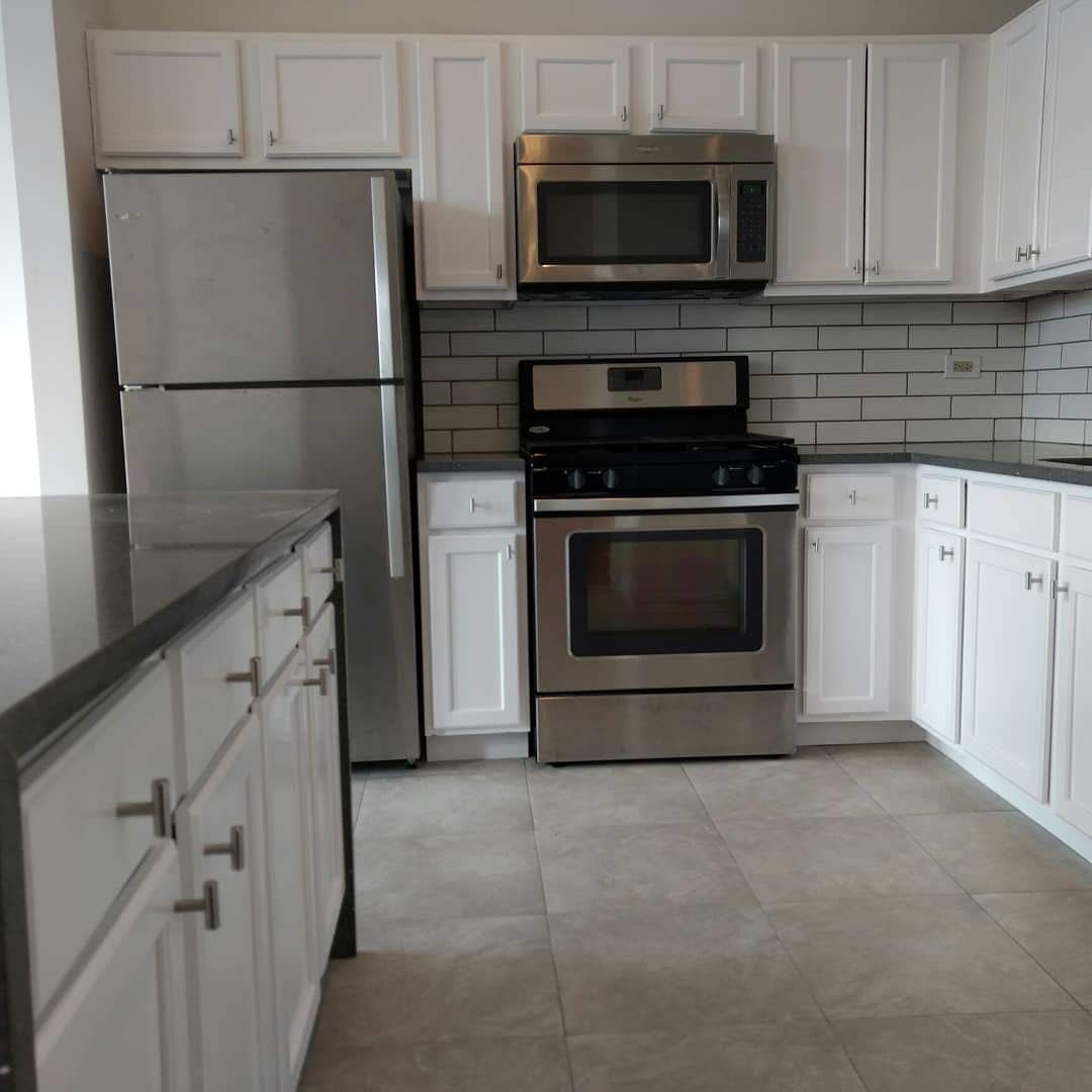 Modern kitchen with stainless steel appliances, white cabinets, and dark countertops.