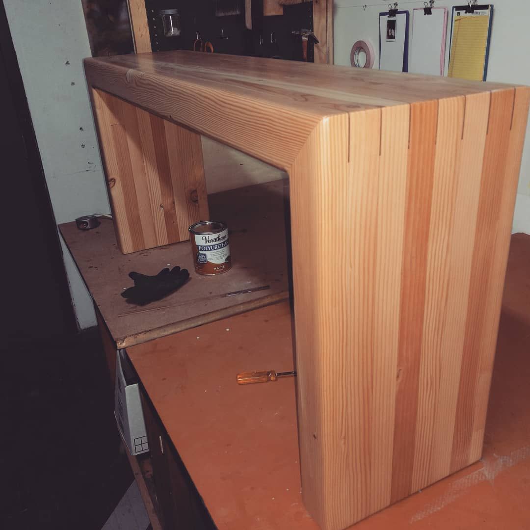 Wooden bench, light-colored, constructed with vertical wood planks, on a workbench.