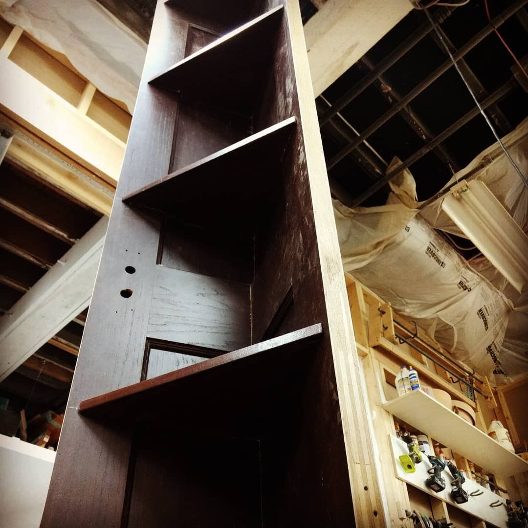 Tall dark brown bookshelf in a room under construction.