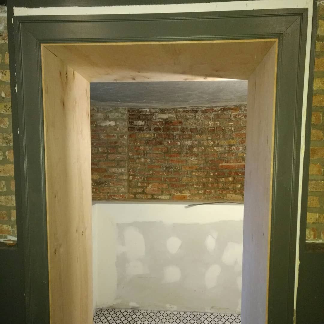 Doorway with dark green trim and exposed brick interior.