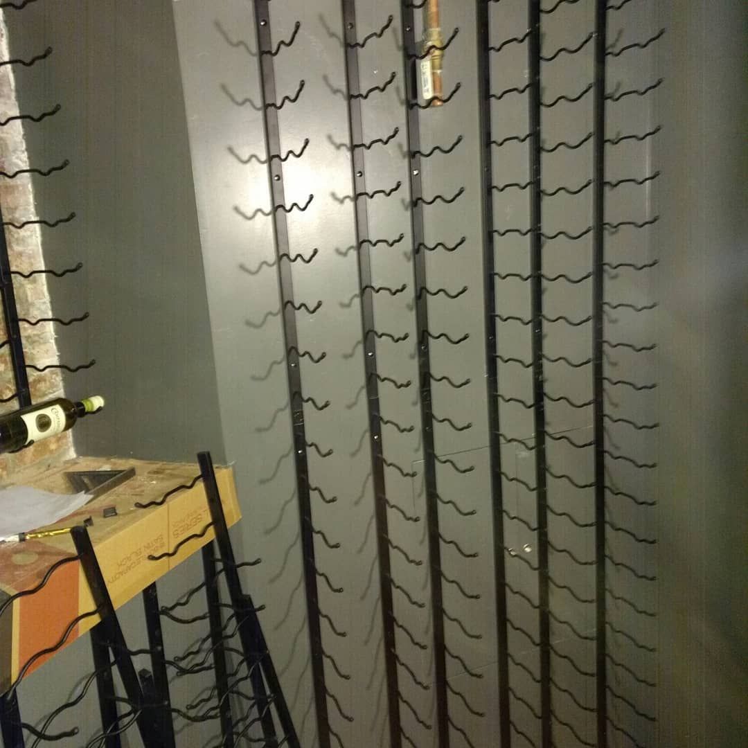 Wine rack attached to a wall with rows of curved metal holders.