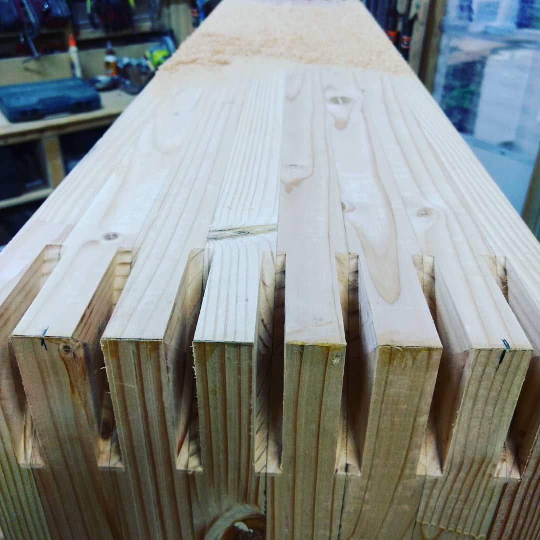 Close-up of a wooden beam with dovetail joints, showcasing construction details in a workshop.
