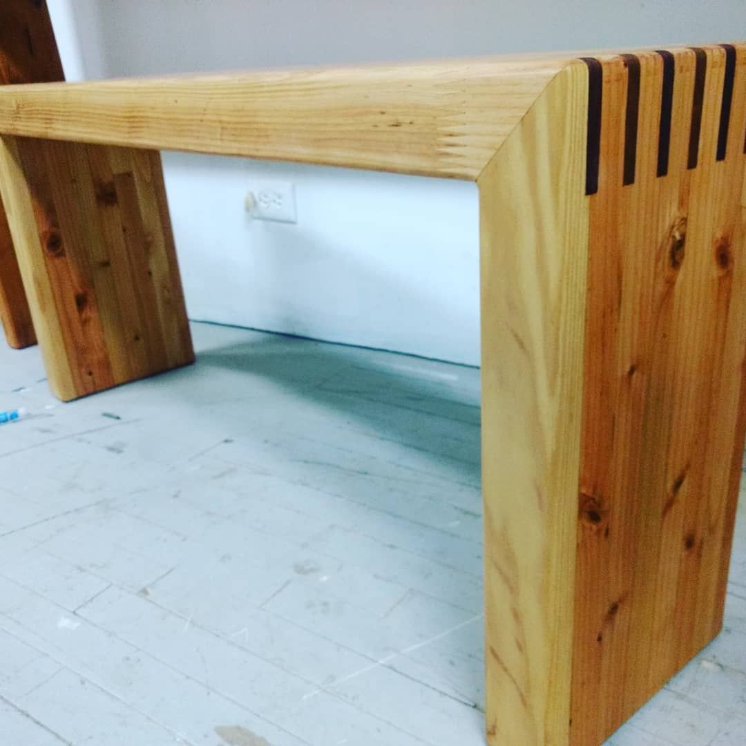 Wooden console table with angled legs and a notched corner detail.
