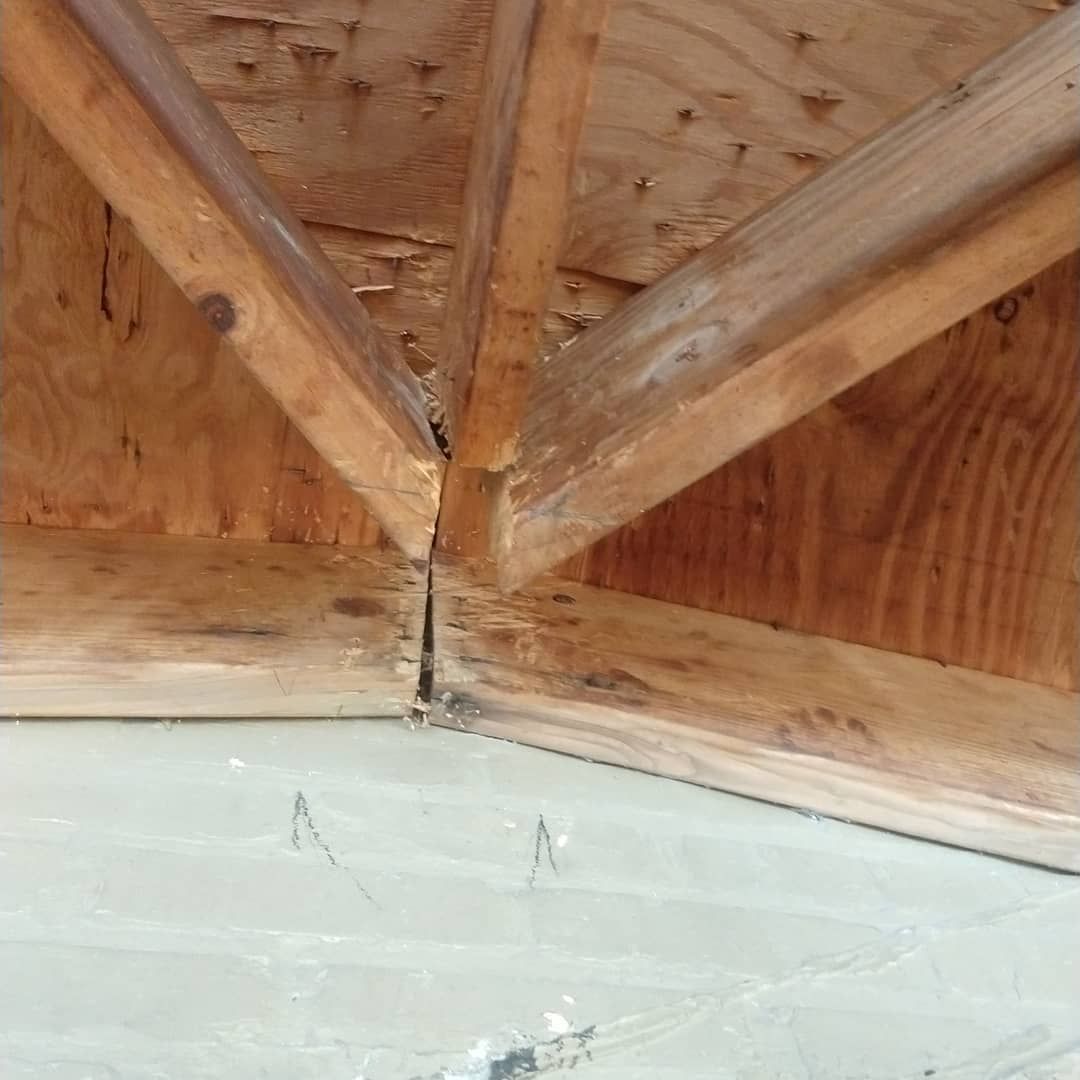 Wooden roof truss, showing a joint where beams converge. Brown wood, interior view.
