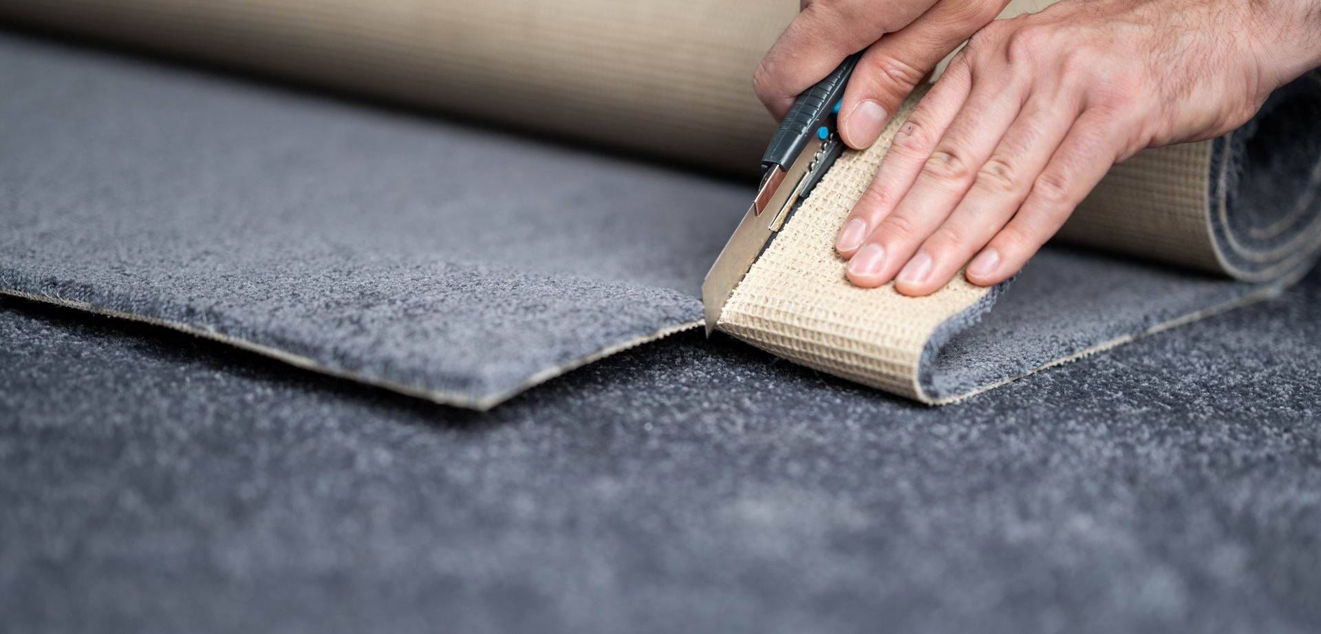 A person is cutting a piece of carpet with a pair of scissors.