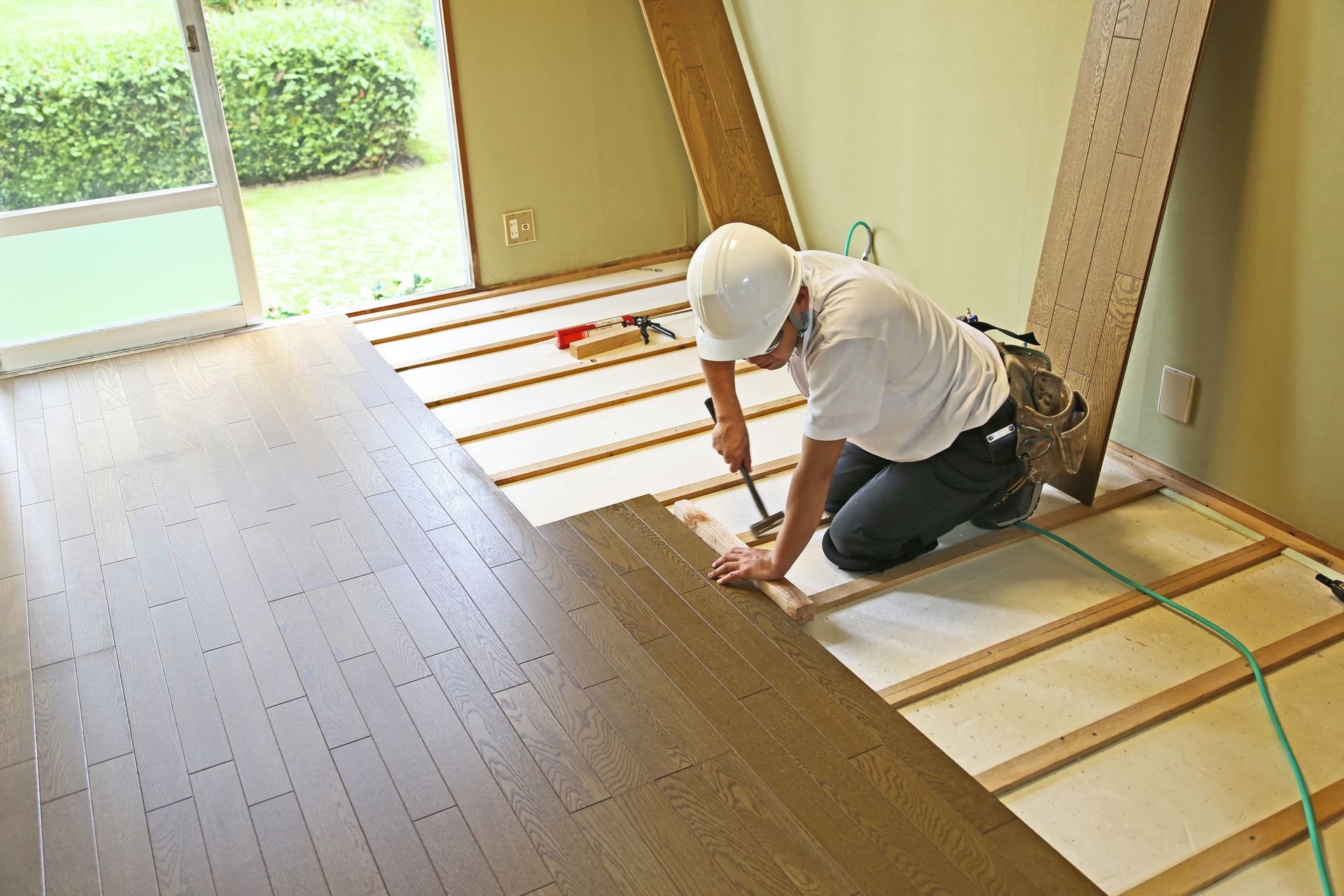 A man is installing a wooden floor in a room.