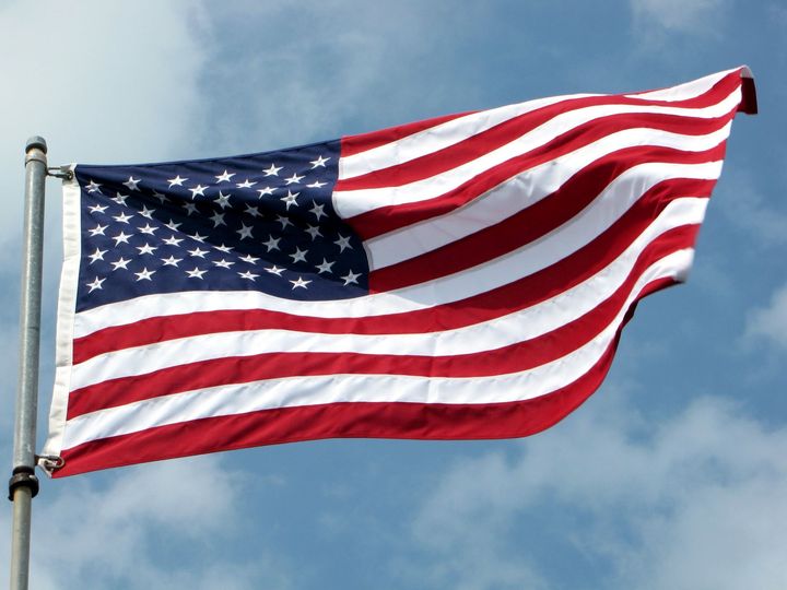 an american flag is waving in the wind against a blue sky