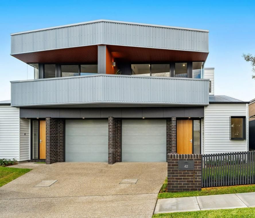 A White House with A Balcony and A Gray Garage Door — Duggan Mather Surveyors in Taylors Beach, NSW