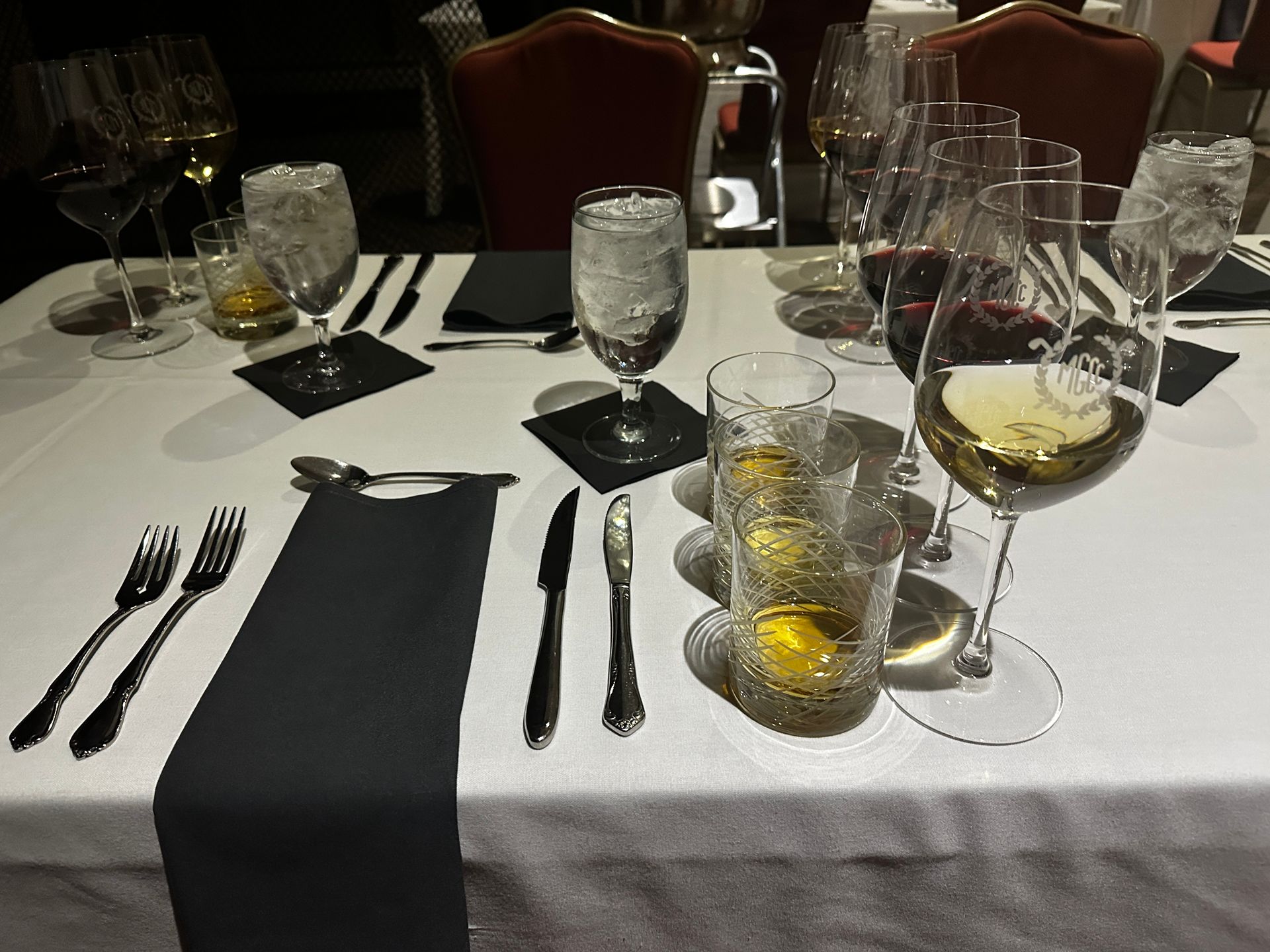 Formal table setting with white tablecloth, multiple wine glasses, and cutlery.