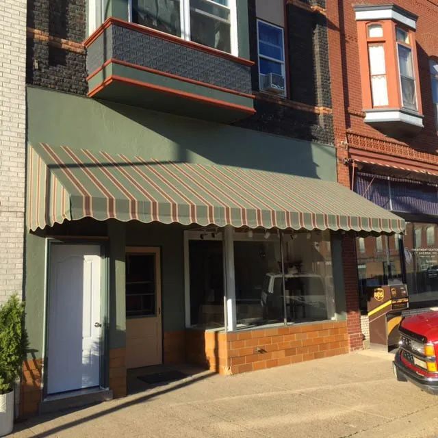 A store front with a striped awning on it.