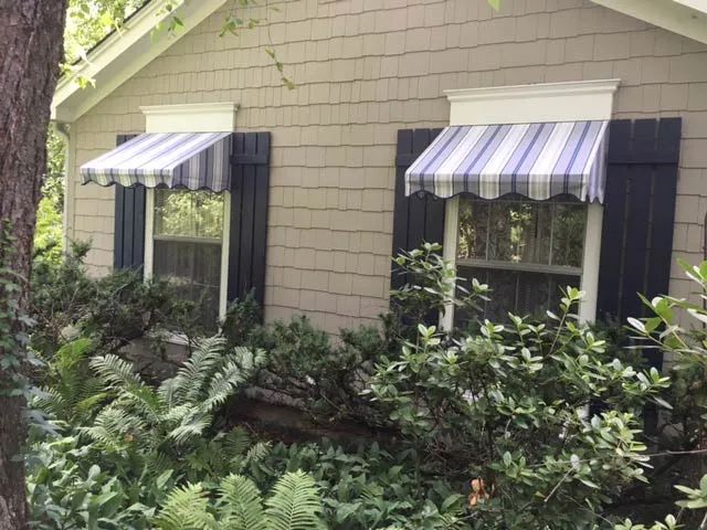 A house with a striped awning on the windows.