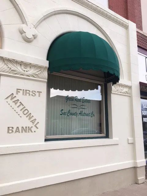 A first national bank building with a green awning over the window.