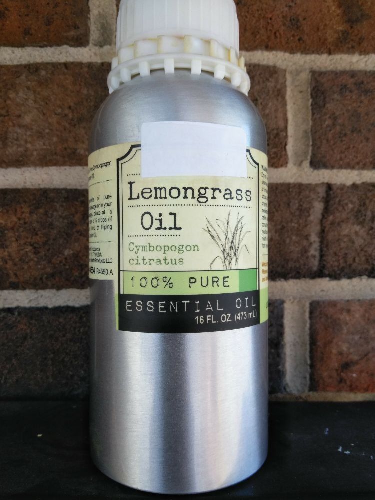 A bottle of 100% pure lemongrass essential oil in a metallic container against a brick background.