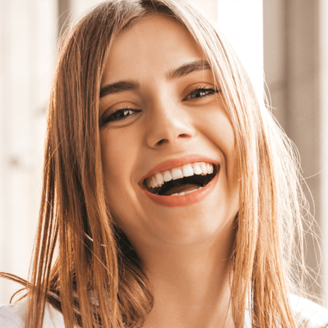 A woman with long hair is smiling with her mouth open.