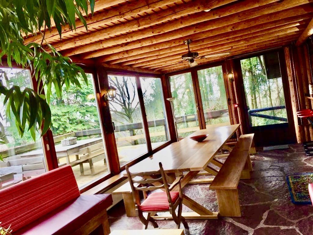 Er staan ​​een tafel en banken in de kamer met veel ramen.