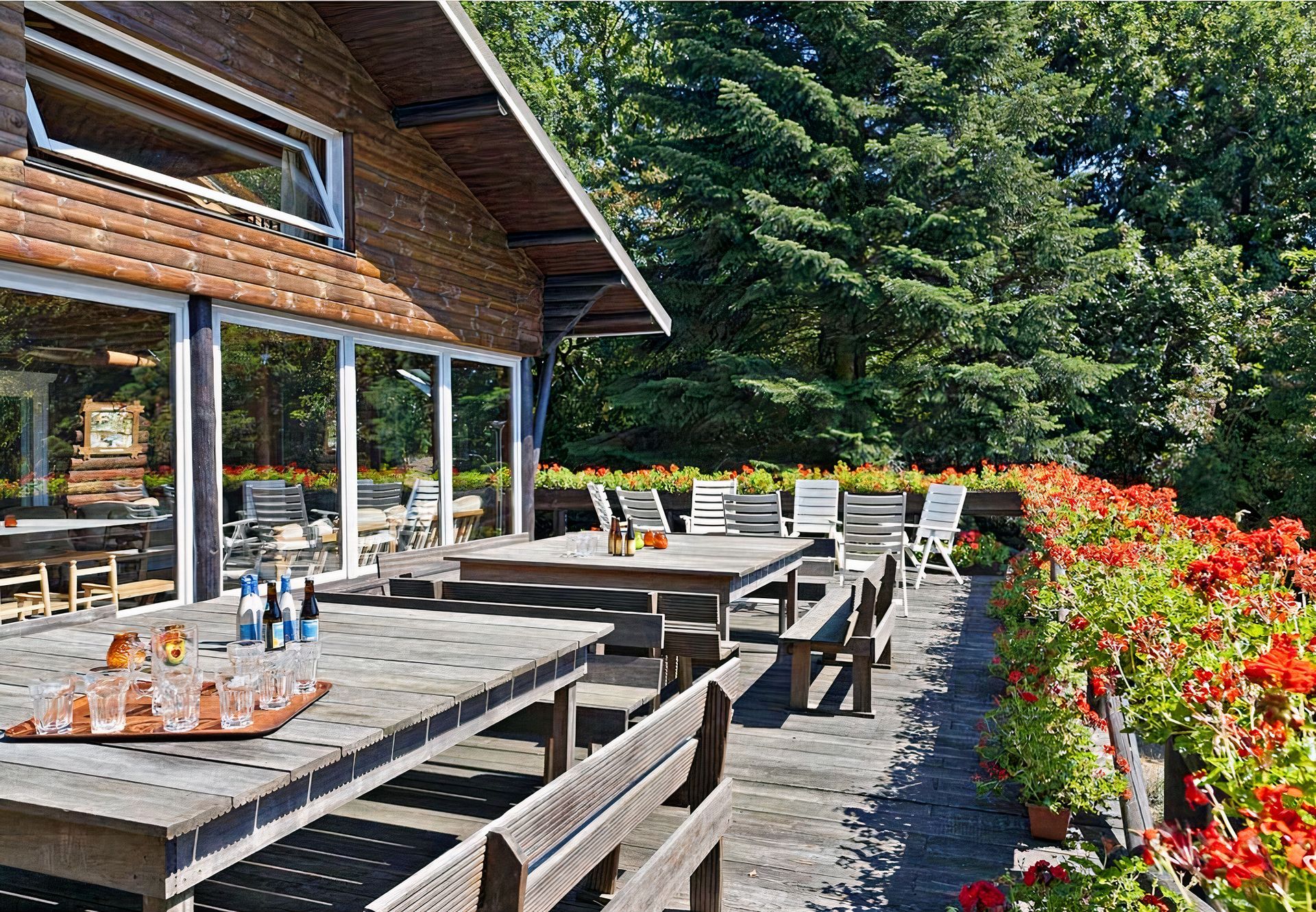 Une terrasse en bois avec des tables et des bancs devant une maison