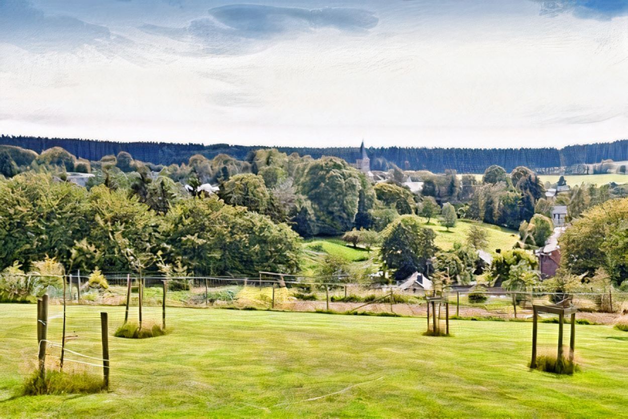 Un champ vert luxuriant avec des arbres et un village en arrière-plan.
