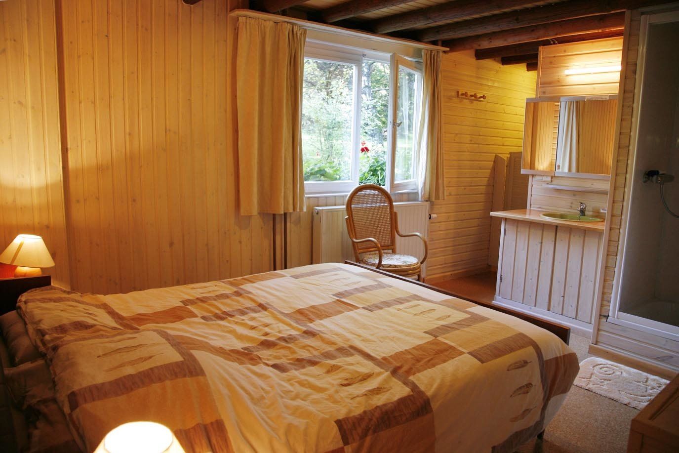 Een slaapkamer met een bed, stoel, wastafel en raam.