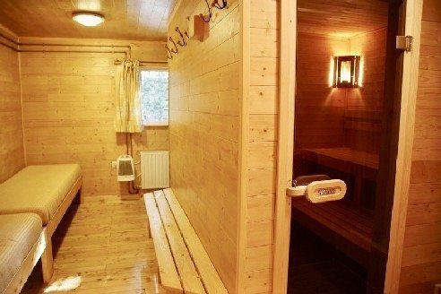 Een houten kamer met een bed en een deur die naar een sauna leidt.
