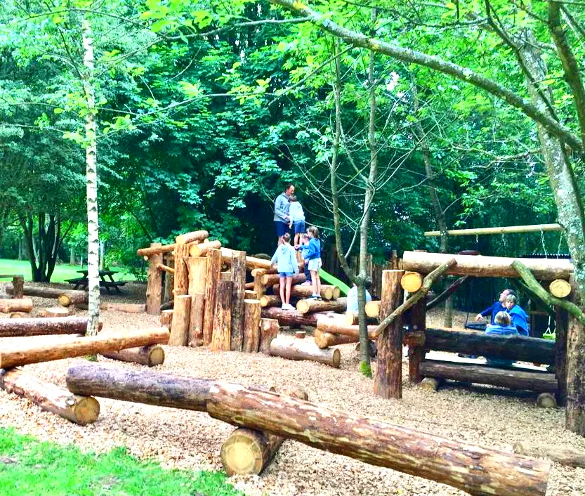 Een groep kinderen speelt op een houten speelplaats.