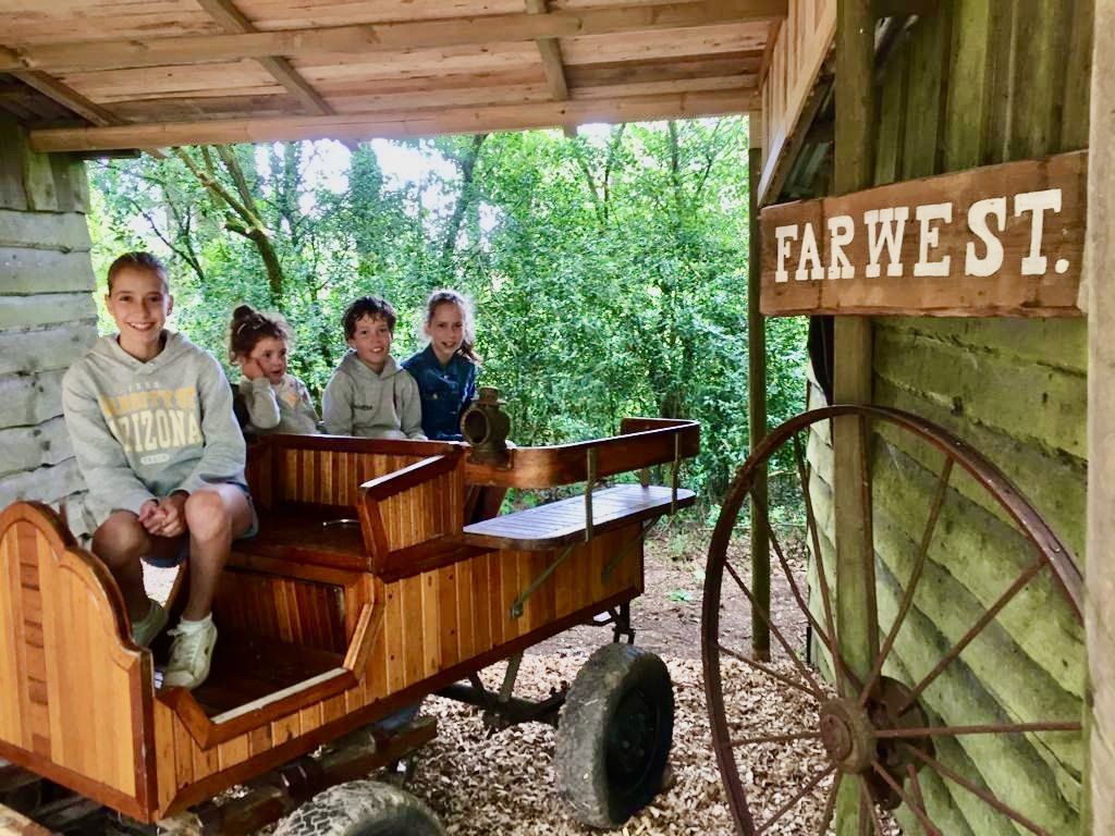 Een groep kinderen zit in een houten wagen.