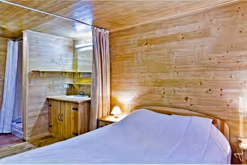 Une chambre avec un lit, une table de nuit, un miroir et des murs en bois.