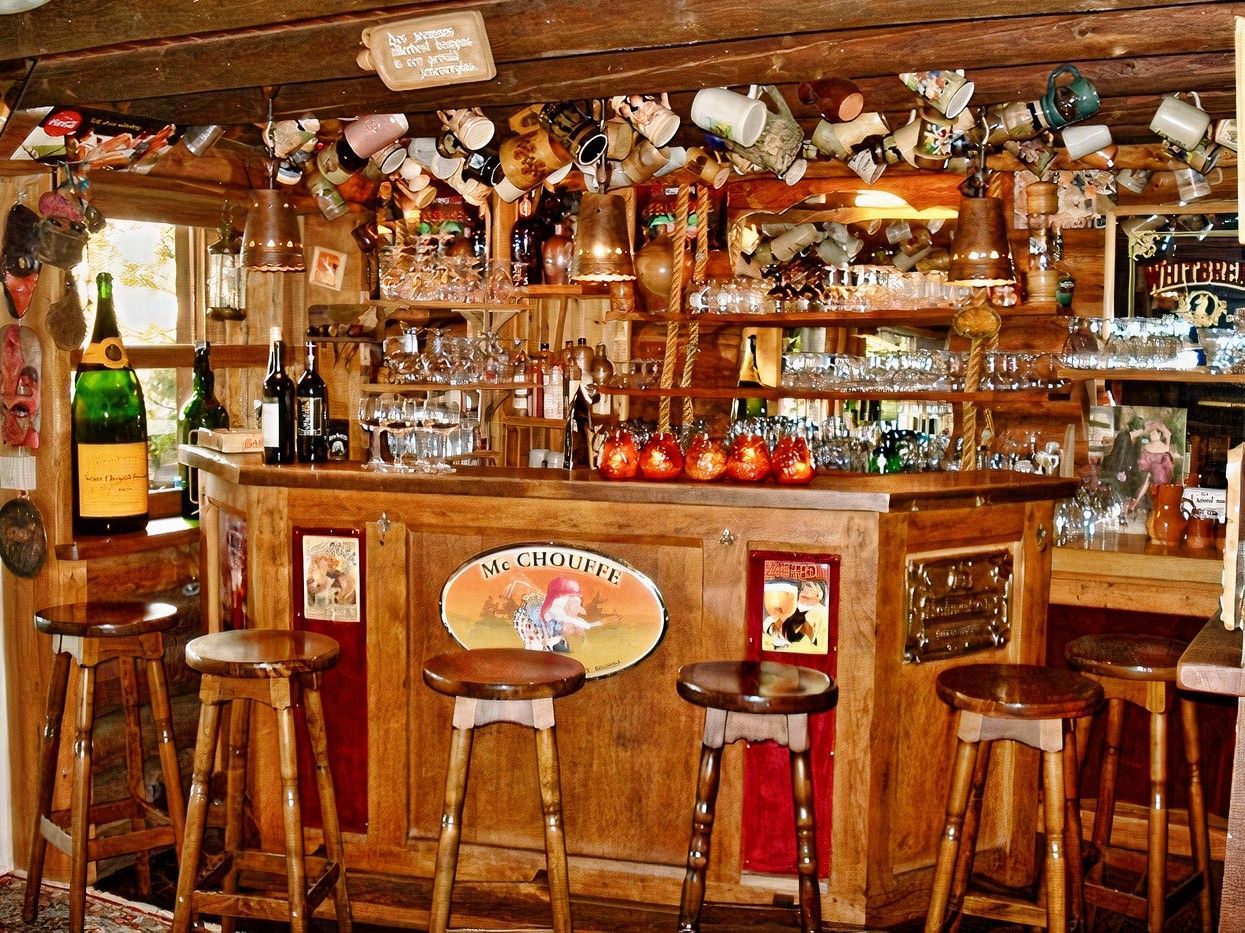 Un bar en bois avec des tabourets et des bouteilles dessus