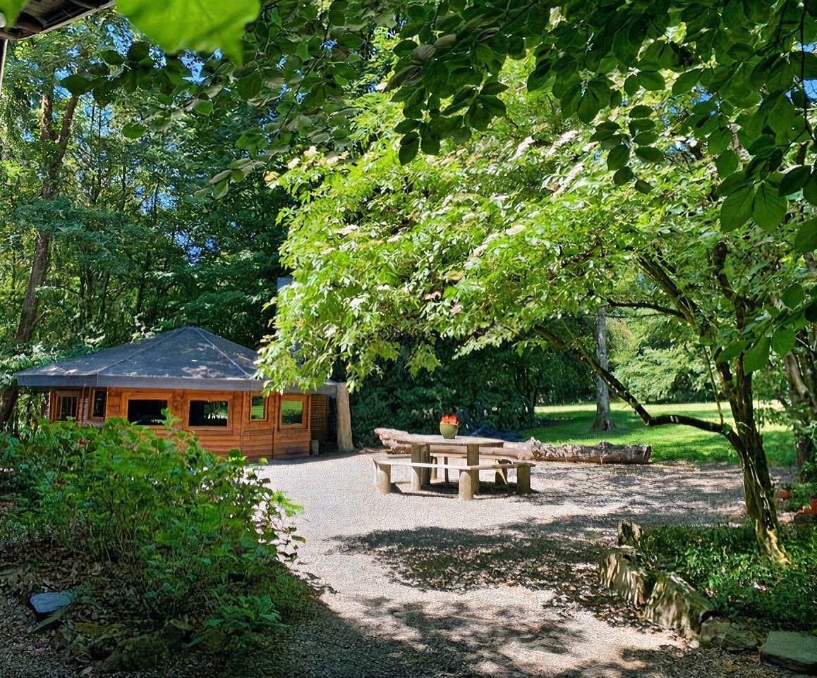 Une aire de pique-nique avec une table en bois et des bancs au milieu d'une forêt.