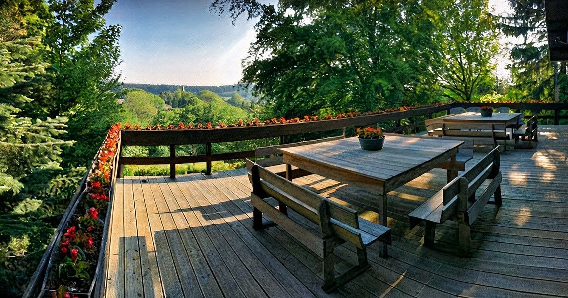 Une terrasse en bois avec une table et des bancs donnant sur une forêt.