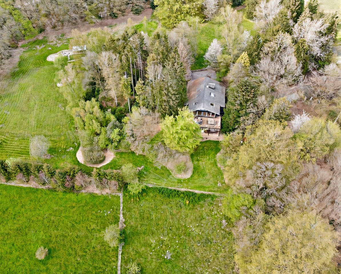 Une vue aérienne d'une maison entourée d'arbres et d'herbe.