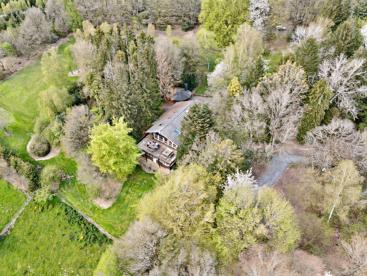 Une vue aérienne d'une maison au milieu d'une forêt entourée d'arbres.